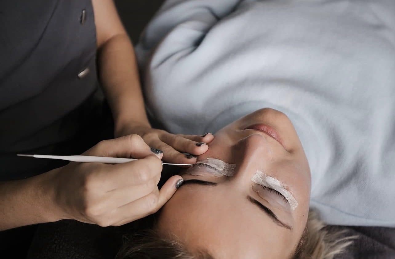 Close-up van een wimperbehandeling: stylist werkt met een fijn instrument aan de wimpers van een klant