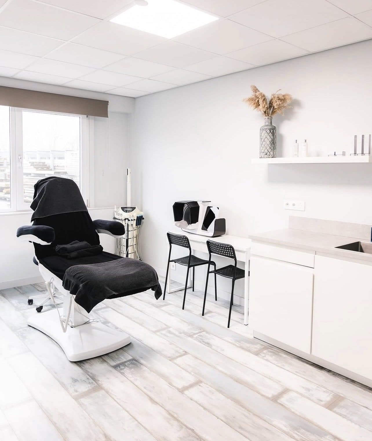 Lichte behandelkamer van een schoonheidssalon met behandelstoel en apparatuur